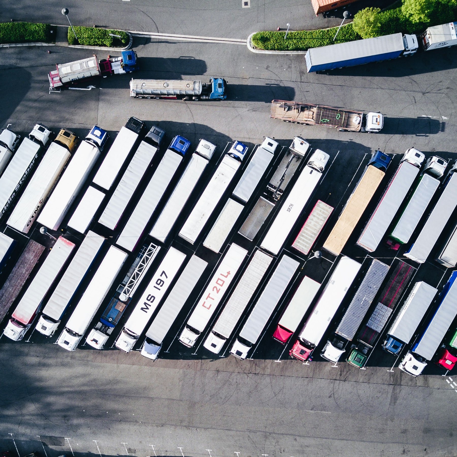 Overhead view of tractor-trailers parked in ordered rows across a yard.