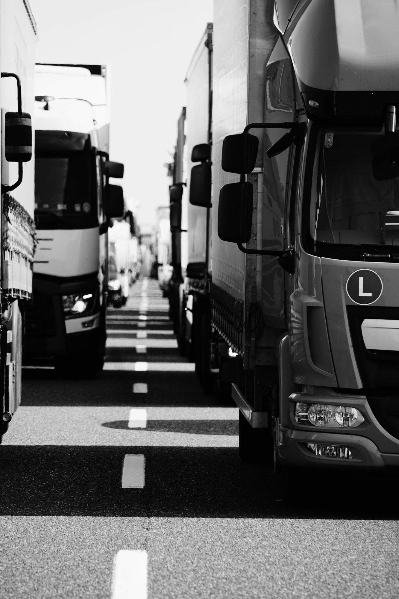 Black and white view down a line of parked tractor units.